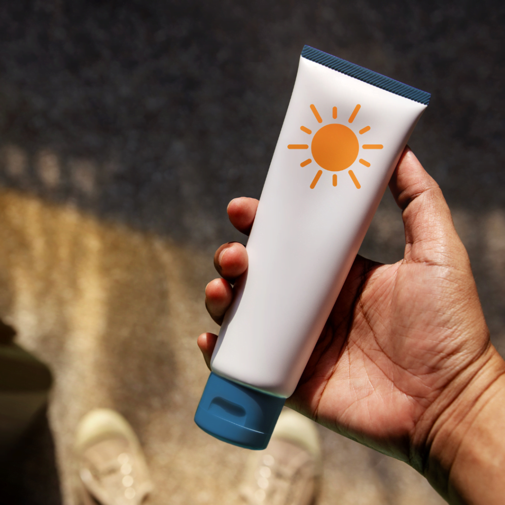 osoba drži spf kremu u ruci dok sttoji na plaži, jer je spf krema neophodna za zaštitu kože od sunca