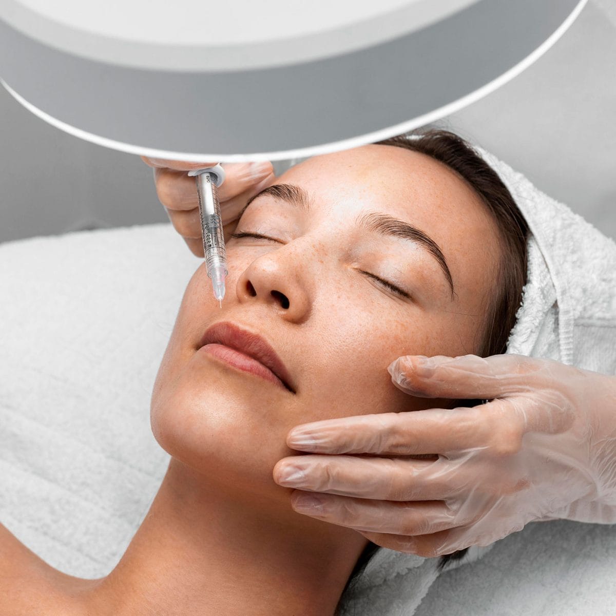 žena leži zatvorenih očiju, a iznad njenih usana nalazi se špric - na korak je od aplikacije filera