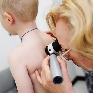 dermatološki pregled u dermatološkoj ordinaciji diva medical u beogradu - doktorka pregleda leđa plavokosog dečaka