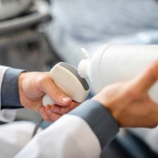 ruke lekara koji nanosi gel na ultrazvučnu sondu, kao deo pripreme za doppler ultrazvuk, nakon koga će se videti doppler indexi