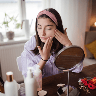 žena nanosi preparate za negu kože lica ispred ogledala